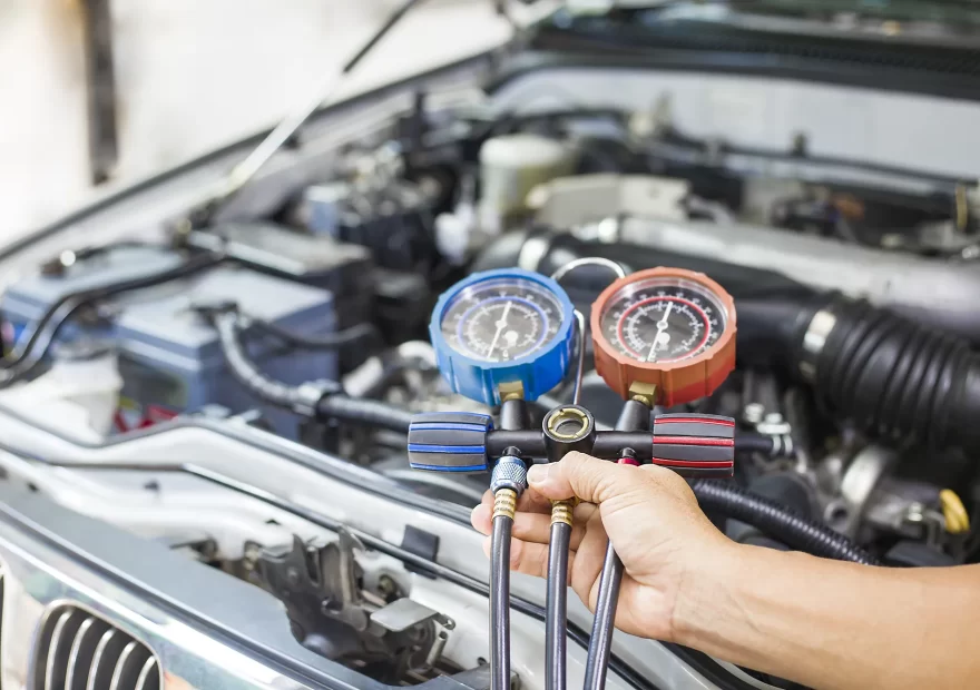 Technician checking car air conditioning pressures with gauges during a regas in Epping