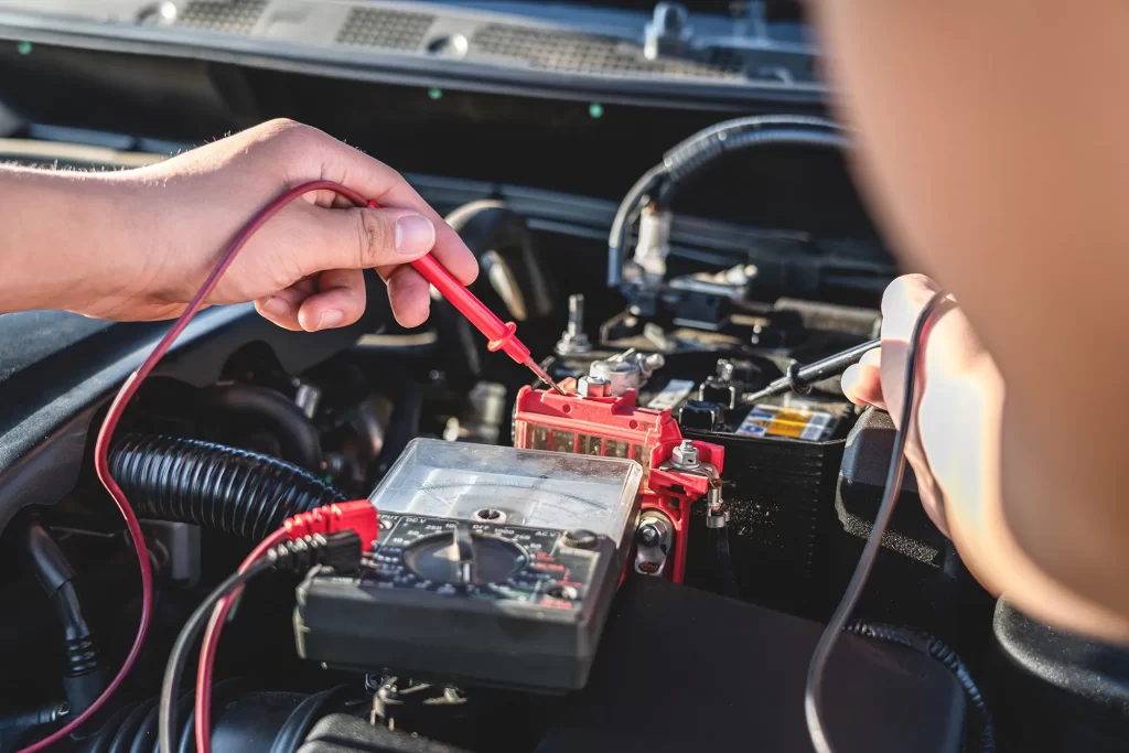 Technician testing a car electrical system with multimeter probes